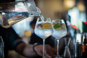 Water is poured into a glass containing sliced fruit or vegetables to make infused water