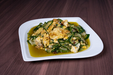 Scrambled eggs with cucumber on a white plate