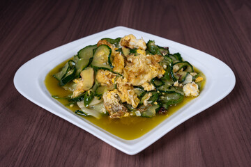 Scrambled eggs with cucumber on a white plate