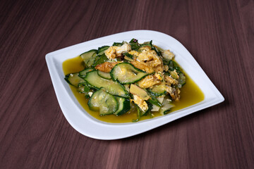 Scrambled eggs with cucumber on a white plate