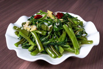 Fried water spinach on a white plate on the table