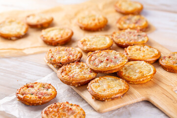 Small tarte flambees or pizzas with cheese, onion and bacon made of pretzel dough