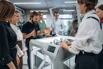 Fototapeta premium Explaining how the device works. People are in the office by the 3d printer