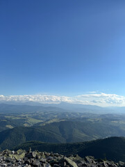 Top view of mountains. Colorful panorama of the mountain, green hills, low clouds, clouds over the mountain. Nature scene of pine trees of Carpathian mountains