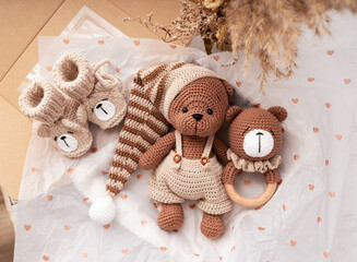 Variety of knitted toys. Bear, baby rattle and baby booties. Handmade soft toys.