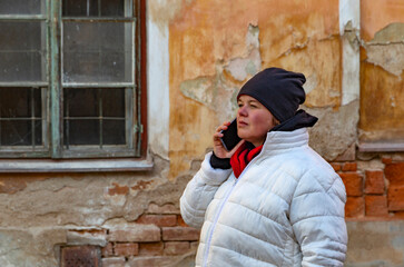 Obraz premium A plus-size woman walking through the streets of a small town and talking on the phone.
