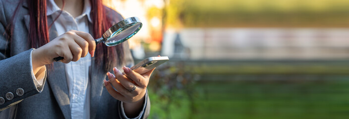 The girl looks into the phone with a magnifying glass, search concept