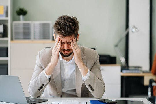 Young stressed caucasian businessman working in the office. Businessman thinking too much work concept in the office.