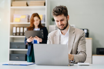 Businessman using laptop computer in office. Happy man, entrepreneur, small business owner working online.