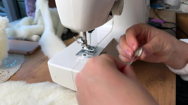 A woman is working at a sewing machine. Threading a needle. Point of view. Close-up.