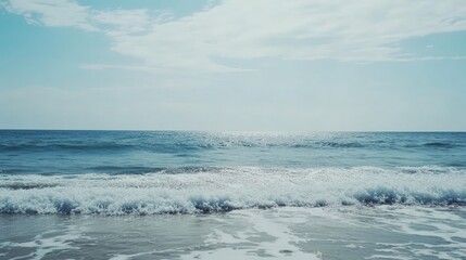 Fototapeta premium Serene Coastal View: Ocean Waves Gently Crashing on the Shore Under a Calm Sky