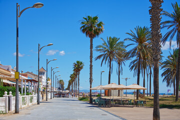 View of a vacations area at the seaside with coffeeshops, palm trees, blue sky and sea