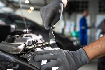 Close up car mechanic hand with mechanic tool fixing car in auto repair service shop