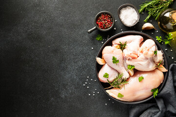 Chicken wing, raw chicken meat with herbs. Top view with copy space on black table.