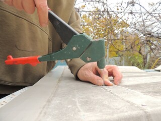 craftsman holding a clamp and a riveter and metal material for fixing parts, working with fasteners...