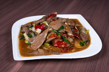 Pork liver with hot and sour pickled peppers on a white plate