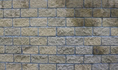 decorative finishing stone in the form of blocks in a fragment of a house wall or fence, stone graphic texture with rectangular shapes of gray-brown color with traces of moisture