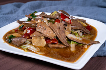 Pork liver with hot and sour pickled peppers on a white plate