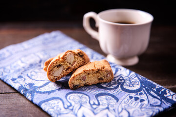 Cantuccini (Italian cookies) and a cup of coffee on dark wooden background. Close up..