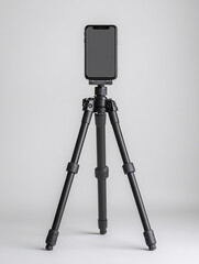 Smartphone on a small black tripod against a white background.