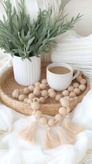 Relaxing setup features a wicker tray with coffee, a green book, and heart-shaped oak beads surrounded by a sage plant.
