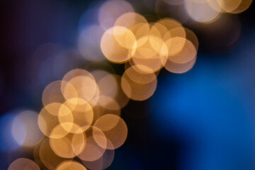 Blurred golden yellow bokeh on light blue gradient background. Abstract defocused blinking lights. Banner for text about holiday sales. Christmas and New Year.