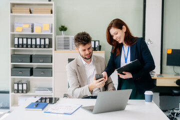 Fototapeta premium Two business workers talking on the smartphone and using laptop