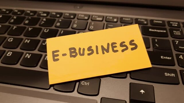 Note with handwritten word e-business lying on computer keyboard. Online commerce, digital marketing concept