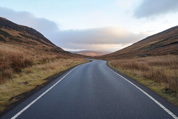 Naklejka premium a road winds through hills under a cloudy sky