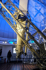 Fototapeta premium Greenwich Observatory telescope, a historic scientific instrument with intricate metal framework, located in the observatory dome, under blue lighting.