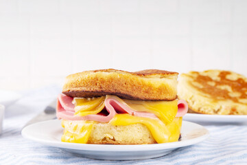 Breakfast crumpet sandwich, british pancake scones burger with cheese and ham, on kitchen table, with stack of crumpets and butter