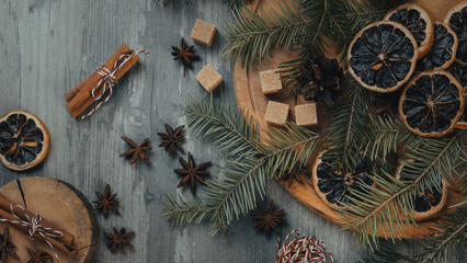 Christmas atmospheric set. Spruce twigs, star anise, cinnamon sticks, dried orange slices, brown sugar on a wooden background.