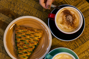 cup of coffee with spinach pie close up photo with human hand. High quality photo