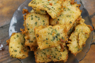 Serving of fried tempeh flour or mendoan cooked in yellowish color on a blue glass plate, photo taken flat lay with a varnished wood background