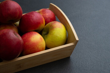 Fresh small organic red apples in a wooden crate on grey table background