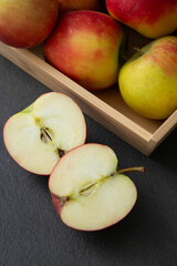 Fresh small organic red apples in a wooden crate on grey table background