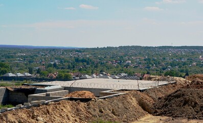 The foundation for a single-family house and the soil on the ground in the background a landscape of mountains with buildings.