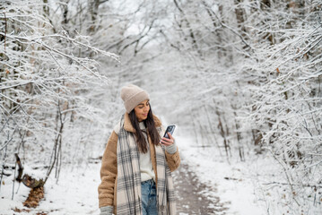 Beautiful Brunette Woman using  phone in the winter forest 