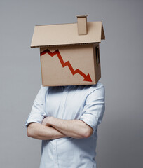 Man with cardboard house on his head and financial chart