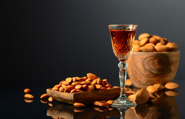Italian liqueur Amaretto with almonds nuts on a black background.