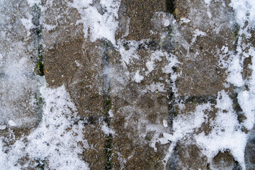 Dangerous snow and ice coating on the paving stone sidewalk not removed by the caretaker - pattern.