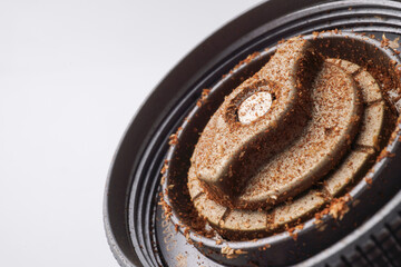 The setting dial or adjustment knob at the bottom of the hand coffee grinder is dirty, covered with coffee grounds that have stuck and needs to be cleaned as part of maintenance. Isolated on white
