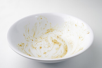 Empty dish plate with traces and pieces of food. Finished White bowl with Spoon and Fork. Isolated on white background
