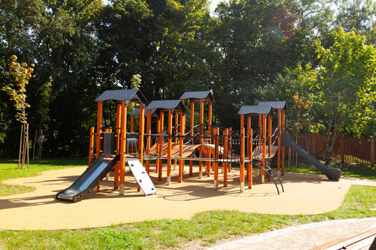 Modern playground nestled in a leafy park, offering various play structures for children of different ages.