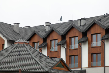 Fototapeta premium Modern residential building with dark gray shingle roofs and wood siding. Clean lines and contemporary design.