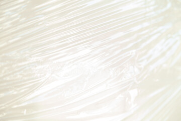 Obraz premium Abstract background of translucent plastic wrap with subtle texture and folds, creating a smooth, flowing pattern of light and shadow.