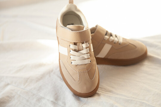 Beige children's sneakers with velcro straps and white stripes. Comfortable and stylish footwear for kids.