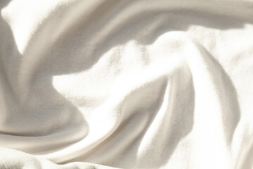 Soft, creamy fabric texture.  Sunlight illuminating delicate folds and wrinkles. Luxurious and elegant textile background.