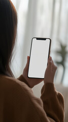 young woman holding smartphone with blank screen, indoors