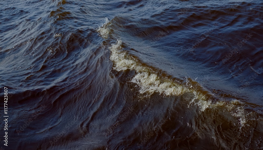 Poster close-up view of gentle brownish waves with sparkling droplets on windy water surface, capturing nat
